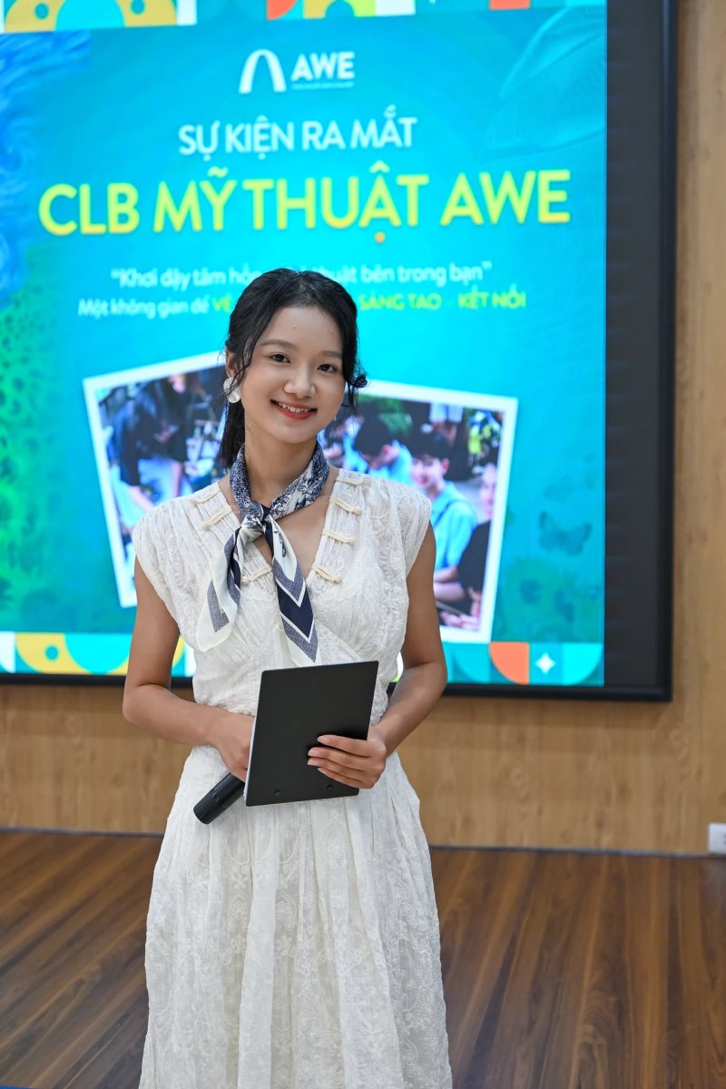 Người dẫn chương trình đứng trước màn hình sự kiện ra mắt CLB Mỹ thuật AWE